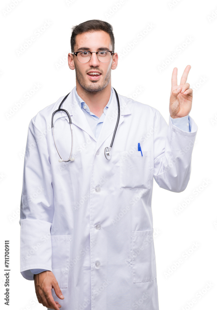 Handsome young doctor man smiling with happy face winking at the camera doing victory sign. Number two. Handsome young doctor man smiling with happy face winking at the camera doing victory sign. Number two.