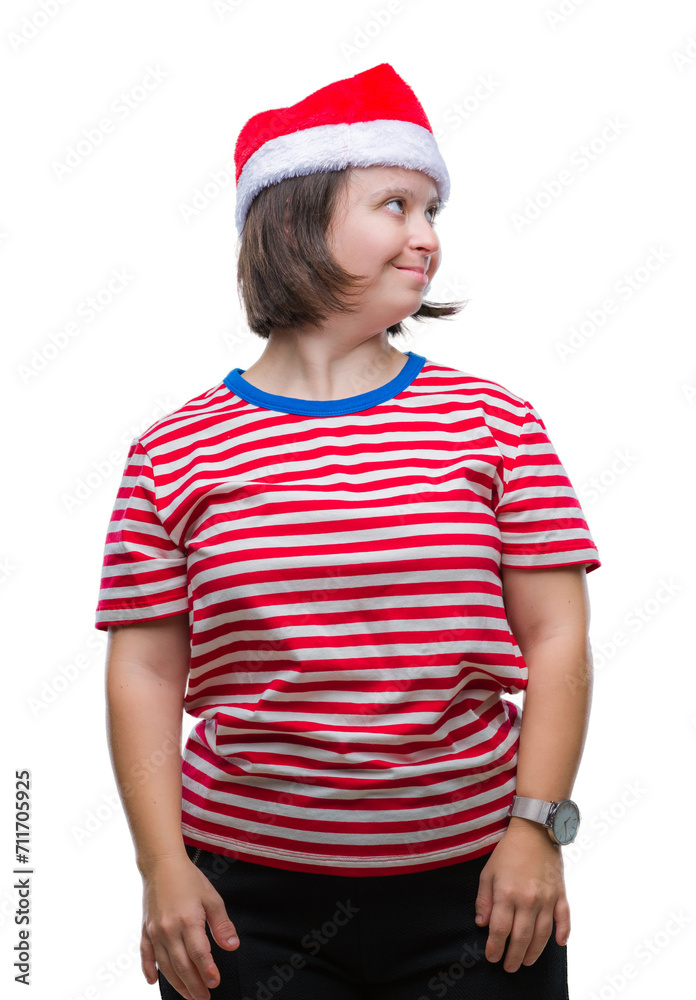 Young adult woman with down syndrome wearing christmas hat over isolated background looking away to side with smile on face, natural expression. Laughing confident.