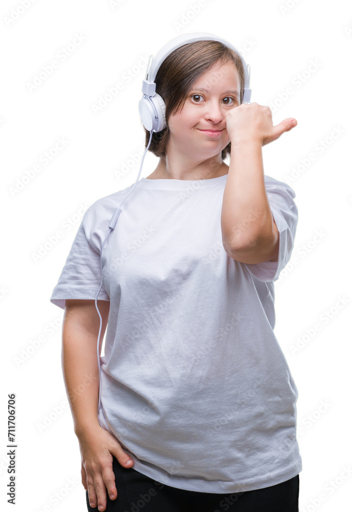 Young adult woman with down syndrome wearing headphones over isolated background smiling with happy face looking and pointing to the side with thumb up. Young adult woman with down syndrome wearing headphones over isolated background smiling with happy face looking and pointing to the side with thumb up.
