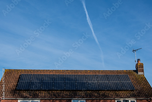 Solar panels on a house roof under a big blue sky. Energy and power harnessing concept.