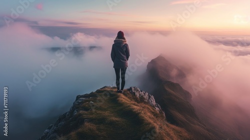 Woman looking at a fog covered valley from behind, standing on the edge of a mountain top generative ai © ThisDesign