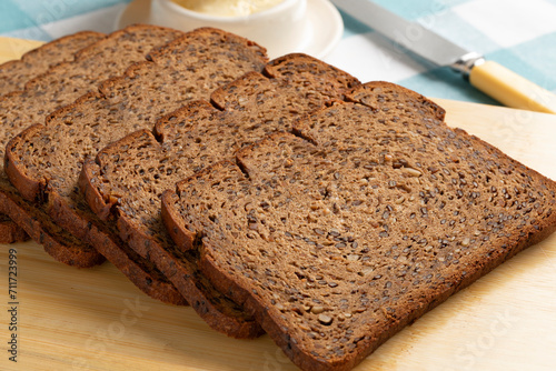 Thin slices of fresh baked brown linseed bread close up on a cutting board