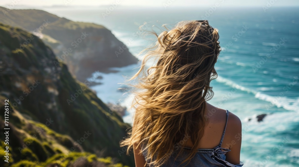 Woman standing on a cliff with her hair caught in the breeze generative ai Woman standing on a cliff with her hair caught in the breeze generative ai