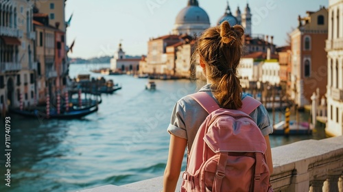 Back view of a young female tourist with a backpack looking at the Grand Canal in Venice, Italy © Obsidian