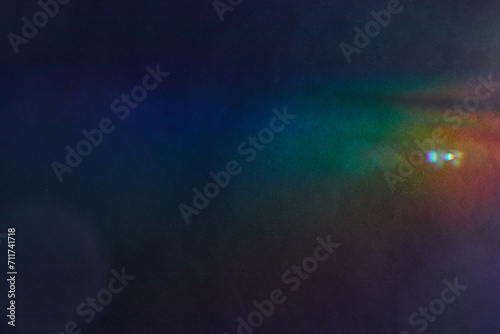 Soft Bright multicolored glare on dark rough textured cardboard. Soft rainbow light. Abstract colorful background. Colorful lens flare leak on a paper texture.