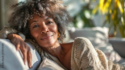 An afro senior woman enjoys a relaxed moment on the sofa at home, embracing a healthy lifestyle and positive vibes. photo
