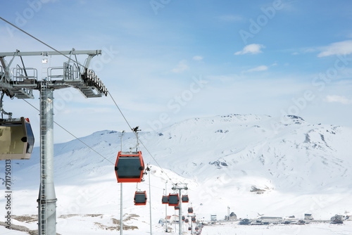 Cable car or ski lift cabins moving against the background of snow-covered mountains and blue sky in the mountain ski resort. Perspective. Winter, Vacation. Extreme sport. Travel content
