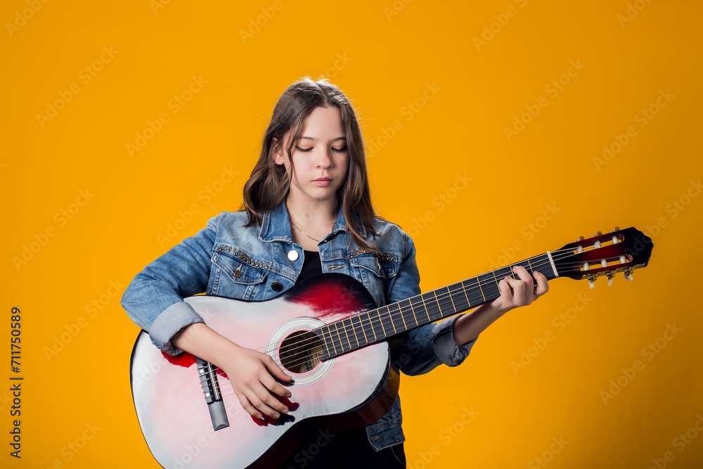 young girl playing guitar on yellow background young girl playing guitar on yellow background