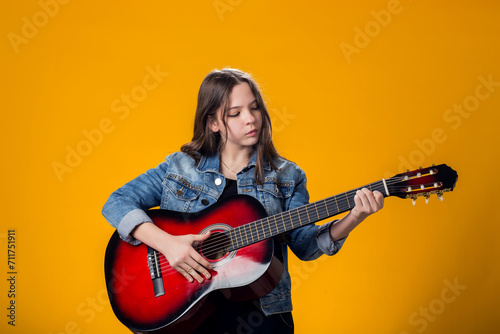 young girl playing guitar on yellow background