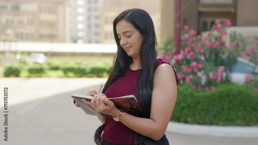 Indian Woman Writing in Notebook while Smiling Indian Woman Writing in Notebook while Smiling