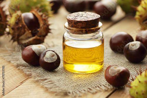 Hourse chestnut oil or extract with seeds on wooden rusric table, closeup, copy space, green medicine, hair and skin care, beauty treatment,  healthcare for leg pain and vein health concept photo