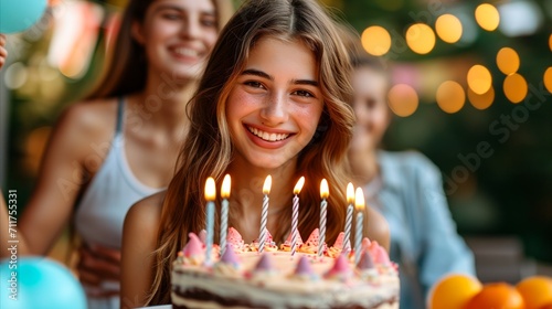Happy teenage girl celebrating birthday party with friends and cake