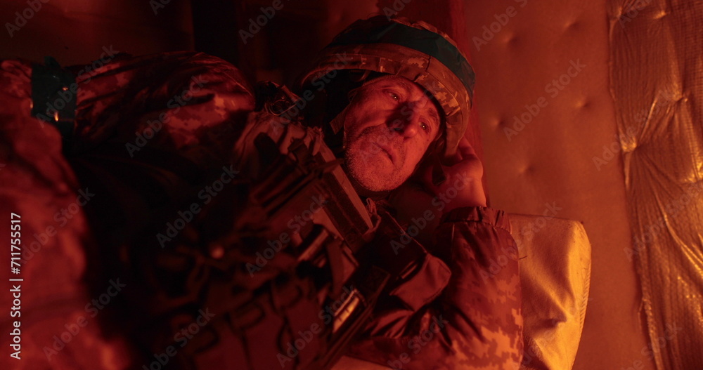 A soldier rests lying in a dugout in the glare of a burning trench candle. Ukrainian soldier in the dugout.