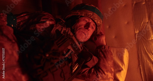 A soldier rests lying in a dugout in the glare of a burning trench candle. Ukrainian soldier in the dugout. © Volodymyr