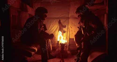 Confession of a Ukrainian soldier in a dark dugout. The chaplain and the warden sit opposite each other and talk. photo