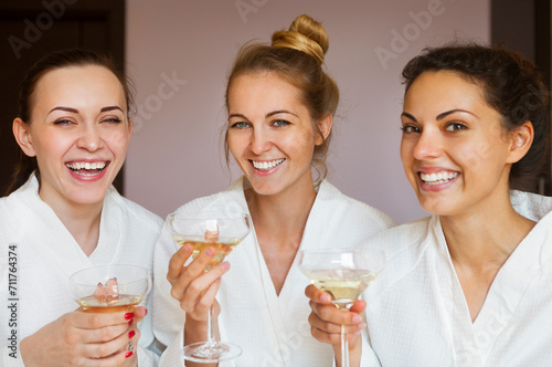 Young happy female friends drinking champagne in spa