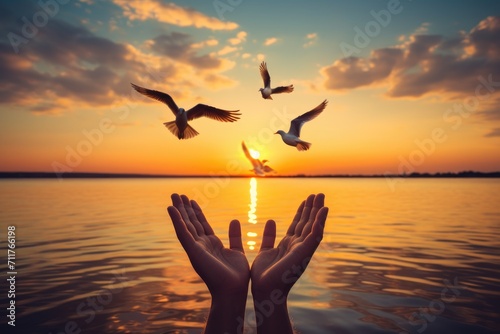 A person stands by the water, palms open, as birds soar by, creating a beautiful moment, Hands open palm up worship with birds flying over calm water sunset background, AI Generated