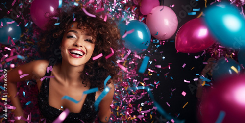 A cheerful young woman in celebrating New Year or Birthday. Celebration in a nightclub, festive, dancing, confetti, fun, dance floor