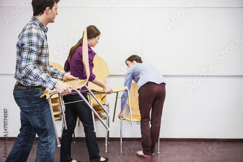 Colleagues stacking chairs in a conference room. Munich, Bavaria, Germany photo