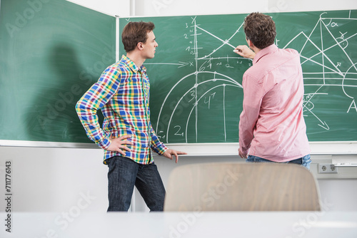 Dozent mit Student im Hörsaal an mathematischen Aufgaben photo