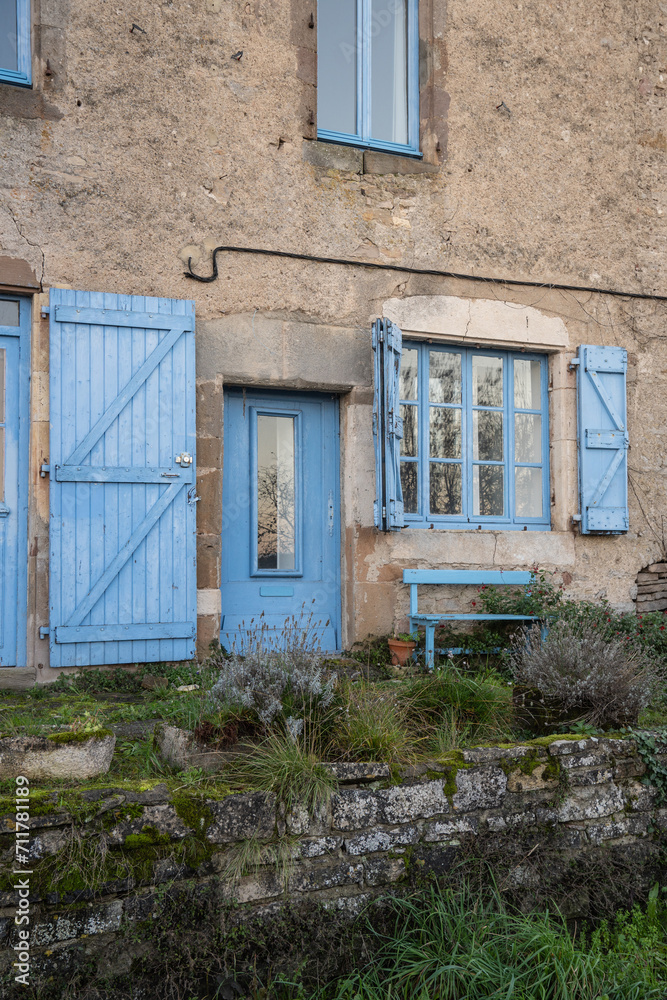 facade of old village house with blue windows and door in french village