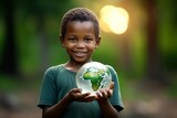 Closeup of an African boy holding a small world ball on an out of focus background of nature. International day of peace concept