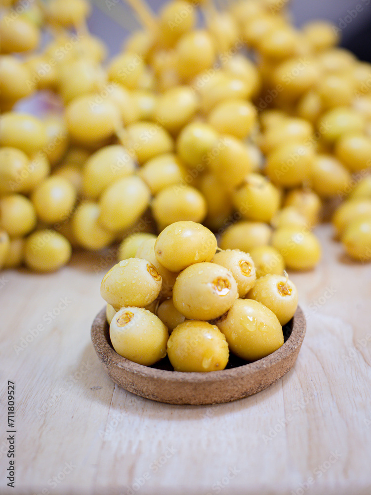 Close up and selective focus fresh dates fruits in wooden bowl. Close up and selective focus fresh dates fruits in wooden bowl.