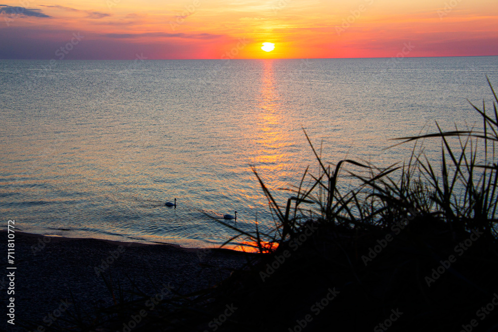 Naklejka premium sunset on the sea. The orange color of the sun is hidden behind the horizon of the sea.