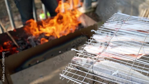 Grill basket with fish against brazier full of burning coals. photo
