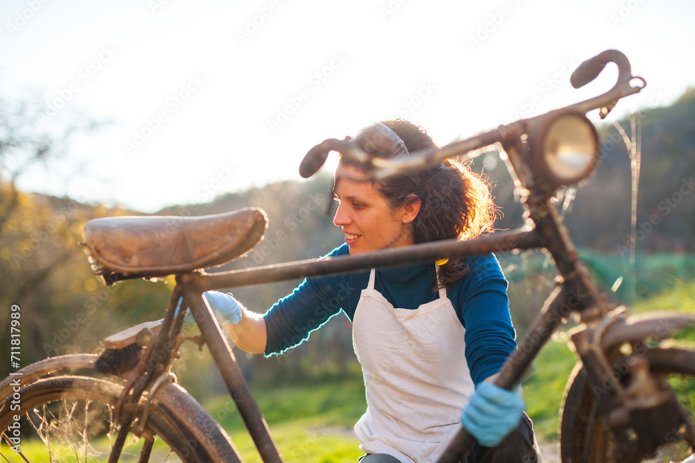 Obraz premium Adult Woman Restorer Begins Renovation of an Old Men's Bicycle from the 1920s