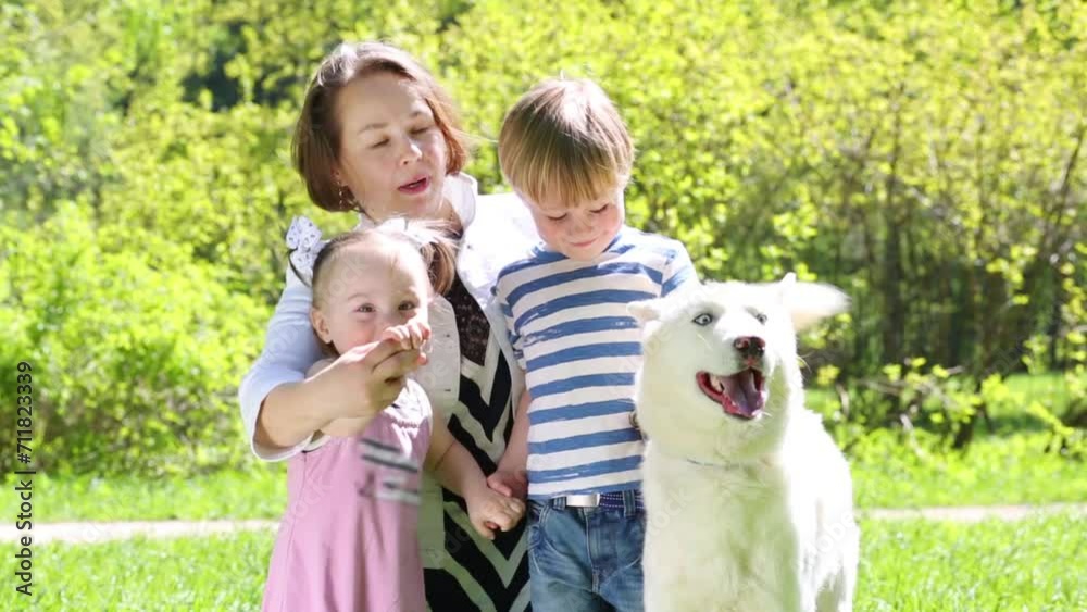 Mother with daughter and son sit with dog on grass in summer park Mother with daughter and son sit with dog on grass in summer park