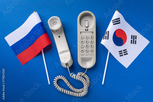 Old telephone and two flags on a blue background, concept on the theme of telephone conversations between South Korea and Russia