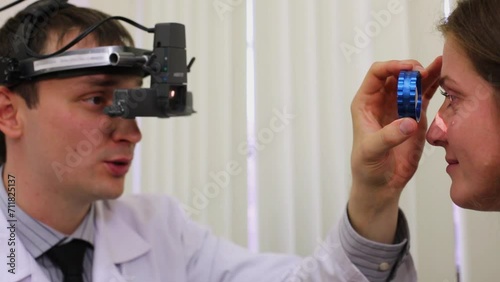 Ophthalmologist examines woman eye through ophthalmoscope. photo