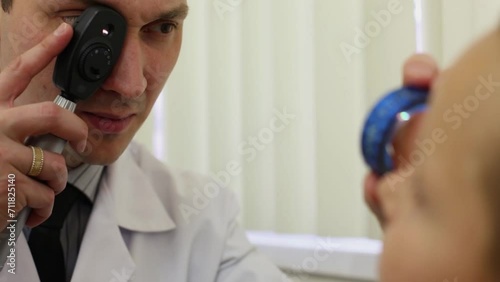 Ophthalmologist inspects eye through lens and direct ophthalmoscope photo