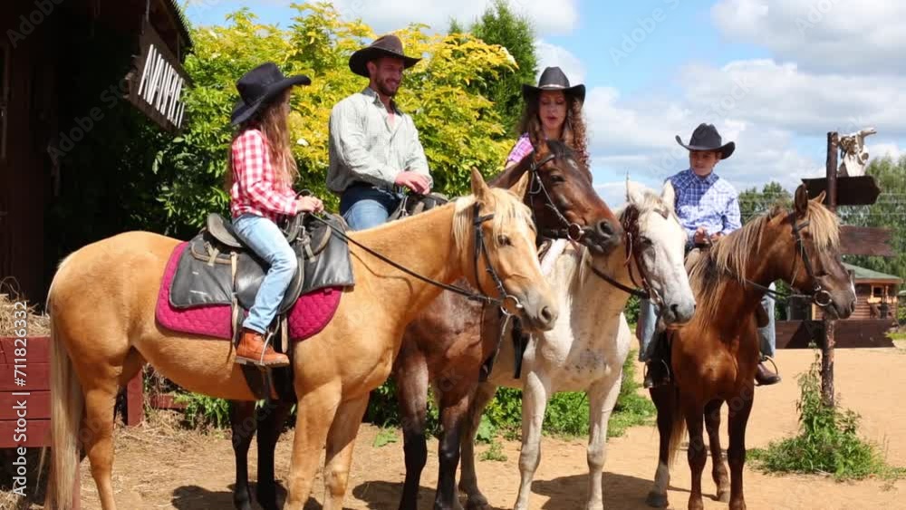 Family of four persons sits on a horses near the saloon. Family of four persons sits on a horses near the saloon.