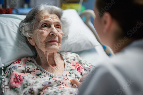 Old Woman Patient Is Looking At Doctor, Nurse Takes Care Of An Old, Sick Woman In Bed At Hospice. photo