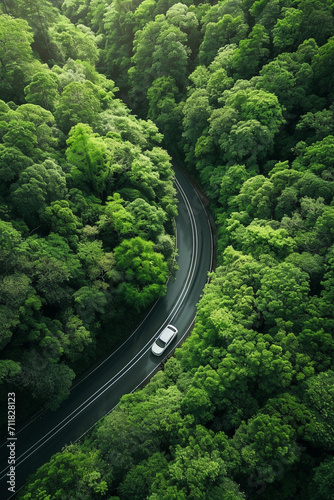 A car driving on a scenic road surrounded by a verdant forest, showcasing sustainable travel The vehicle is an electric model, blending smoothly with the natural environment