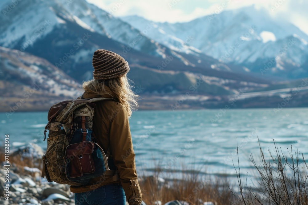 Scandinavian woman in a hat with a backpack on the background of nature and mountains looking at the lake.view from behind