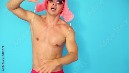 Half-naked man in pink fur cap and sunglasses dances and falls photo