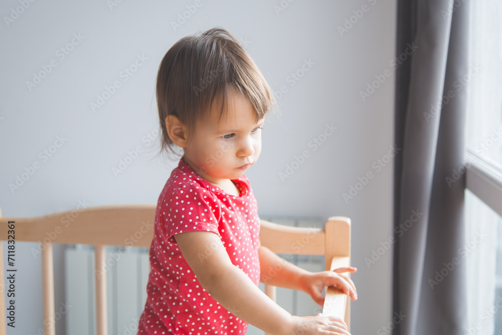 one sad child stands in his crib and looks out the window, waiting for someone. one sad child stands in his crib and looks out the window, waiting for someone.