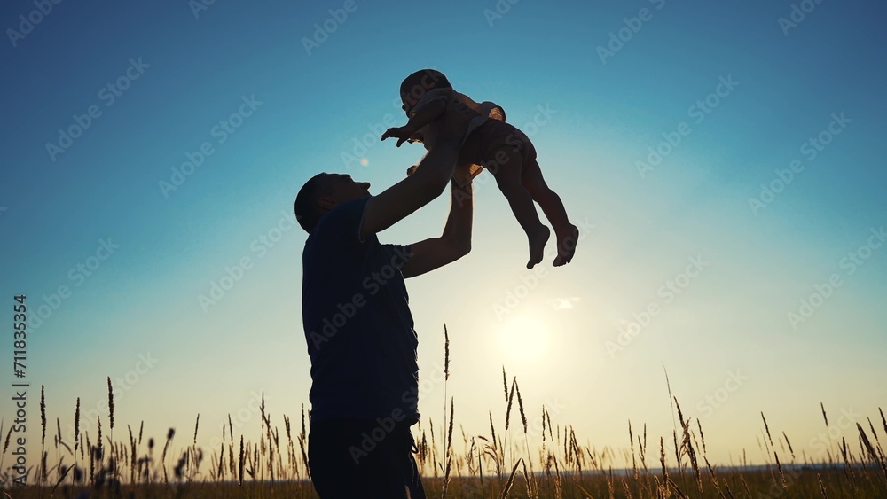 father throws play baby in the park. father's day silhouette happy