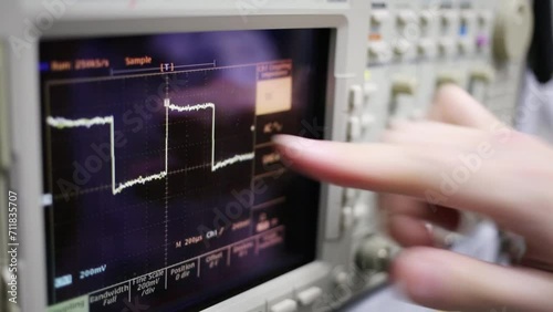 Digital oscilloscope and male hand turns tumblers for setting photo