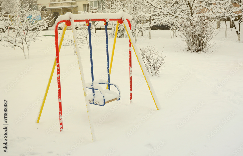 Children's swing, covered with a thick layer of snow after a heavy snowfall Children's swing, covered with a thick layer of snow after a heavy snowfall