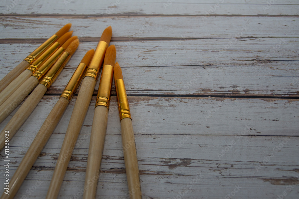 Synthetic brushes with a wooden handle for painting on a wooden table. View from above. The artist's tools. Synthetic brushes with a wooden handle for painting on a wooden table. View from above. The artist's tools.