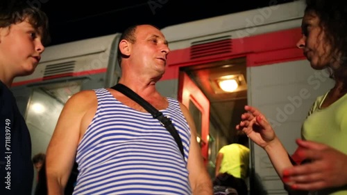 Mother and son talking with his grandfather in vest next to train photo