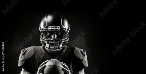 Black and white portrait of an American football player holding rugby ball on a black background with copy space design