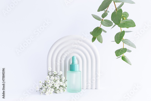 Wallpaper Mural Beautiful composition with glass blue cosmetic bottle with dropper on white background with beautiful flowers, eucalyptus leaves and clay decorations close up. Herbal organic cosmetic concept. Torontodigital.ca