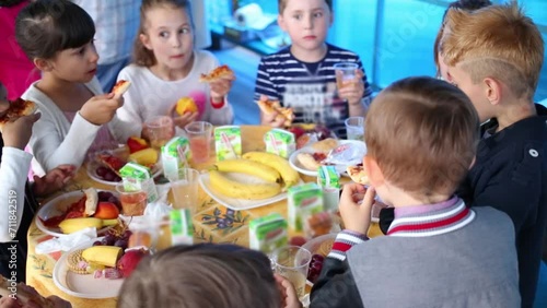 Eight happy children eats sweets at festive table in kindergarten photo