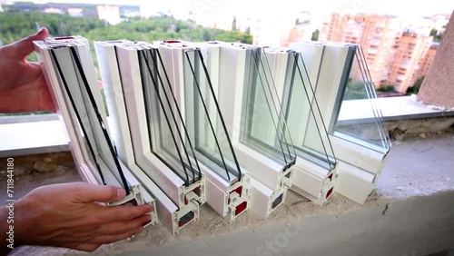 hands take one of six PVC windows samples from concrete windowsill photo
