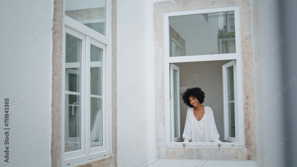 Domestic girl peeping window morning indoors. African lady looking camera alone